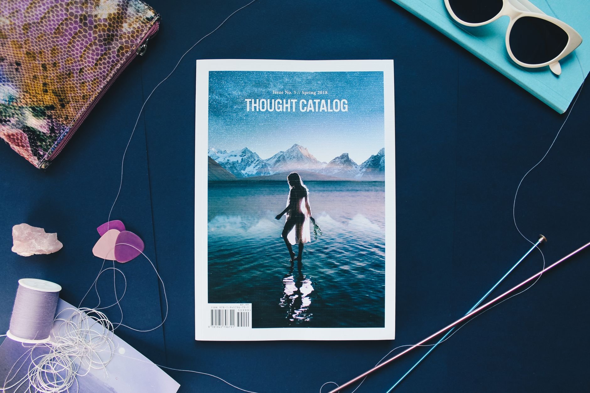 Creative flat lay featuring a magazine with colourful threads and accessories.